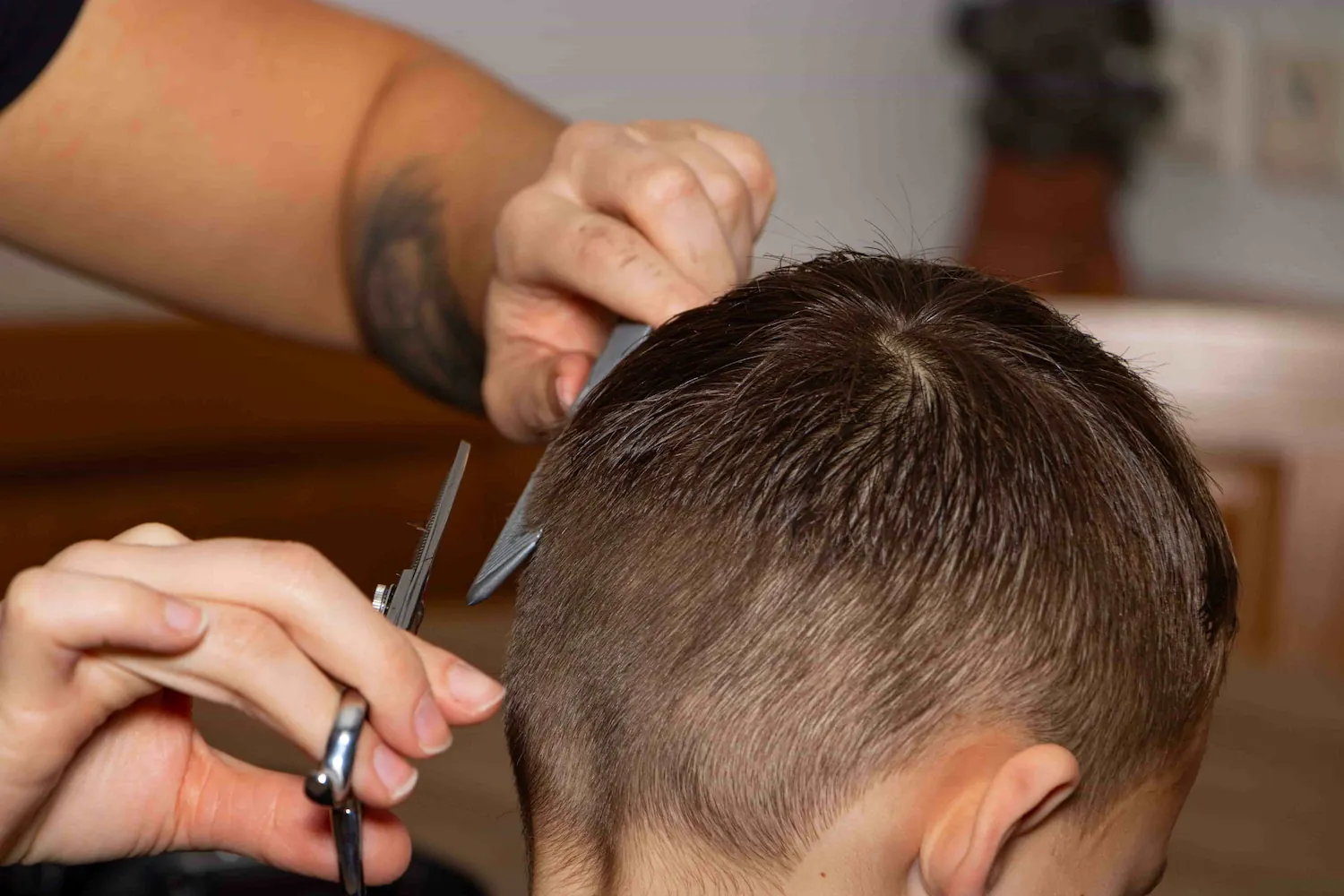 Friseuse schneidet einem Jungen die Haare mit der Schere